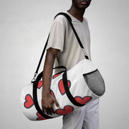 Person holding a white duffel bag with red heart patterns against a plain background