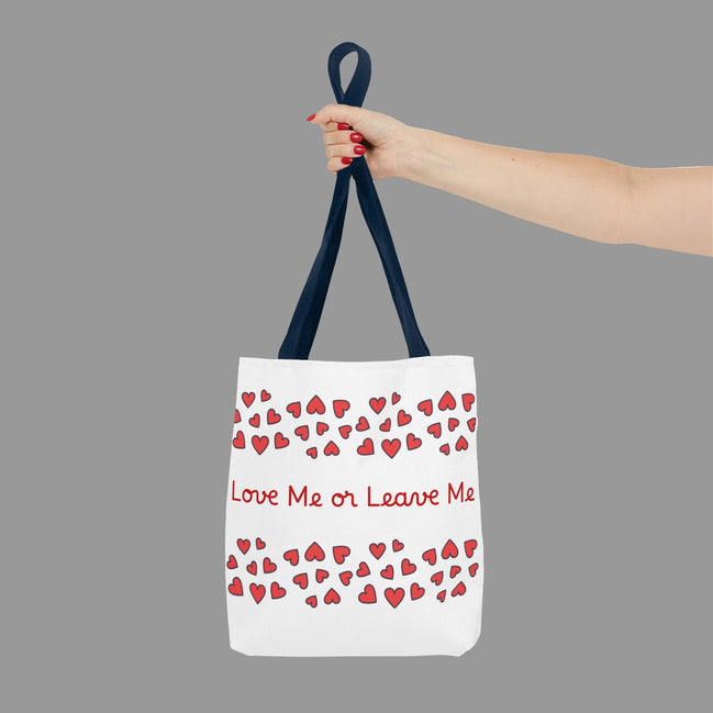 Tote bag with red hearts and text held by a hand on a white background