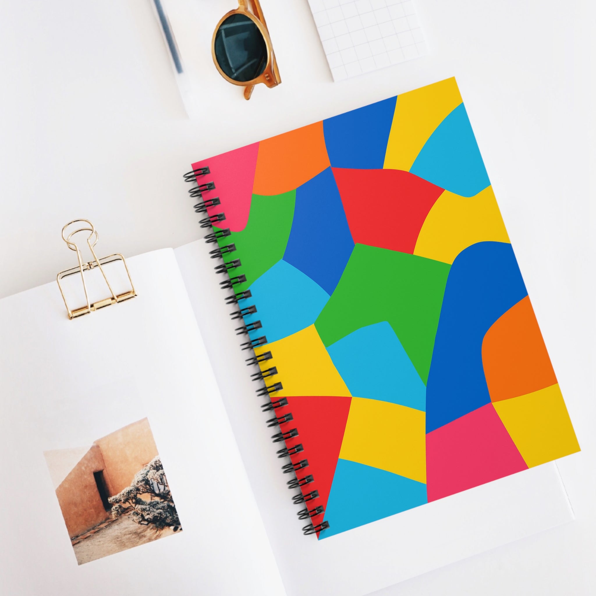 Colorful geometric notebook on a white surface with a photo and clip.