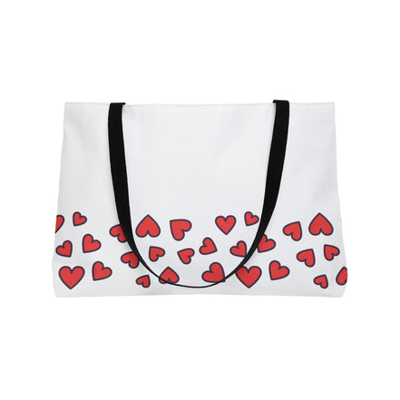 White tote bag with red heart pattern and black straps on a white background