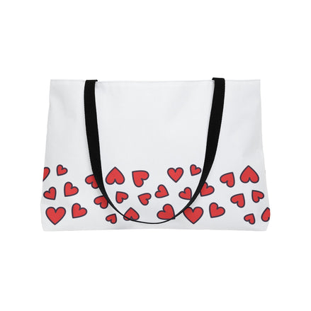White tote bag with red heart pattern and black straps on a white background