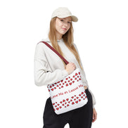 Person holding a white tote bag with red heart patterns and text on a white background