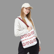 Person holding a white bag with red heart patterns and text on a white background