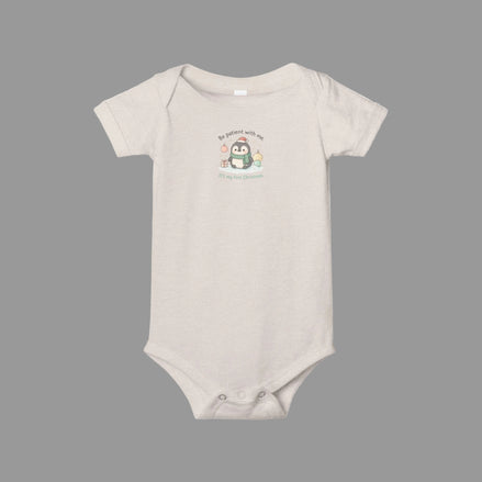 Beige baby onesie with a cartoon penguin design on a white background