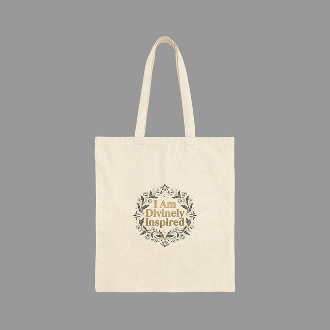 Beige tote bag with 'I Am Divinely Inspired' text and floral design on a white background