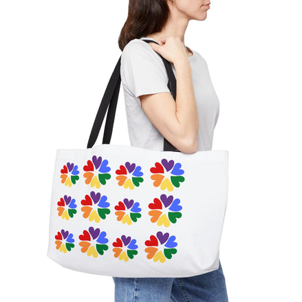 Person holding a white tote bag with colorful flower patterns on a white background