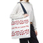 Person holding a tote bag with red hearts and text on a white background