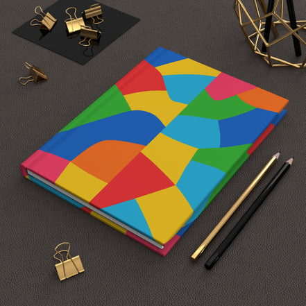 Colorful geometric notebook on a dark surface with office supplies.