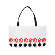 White tote bag with red floral pattern and black accents on a white background