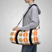 Person carrying a small white duffel bag with orange and brown patterns on a plain background