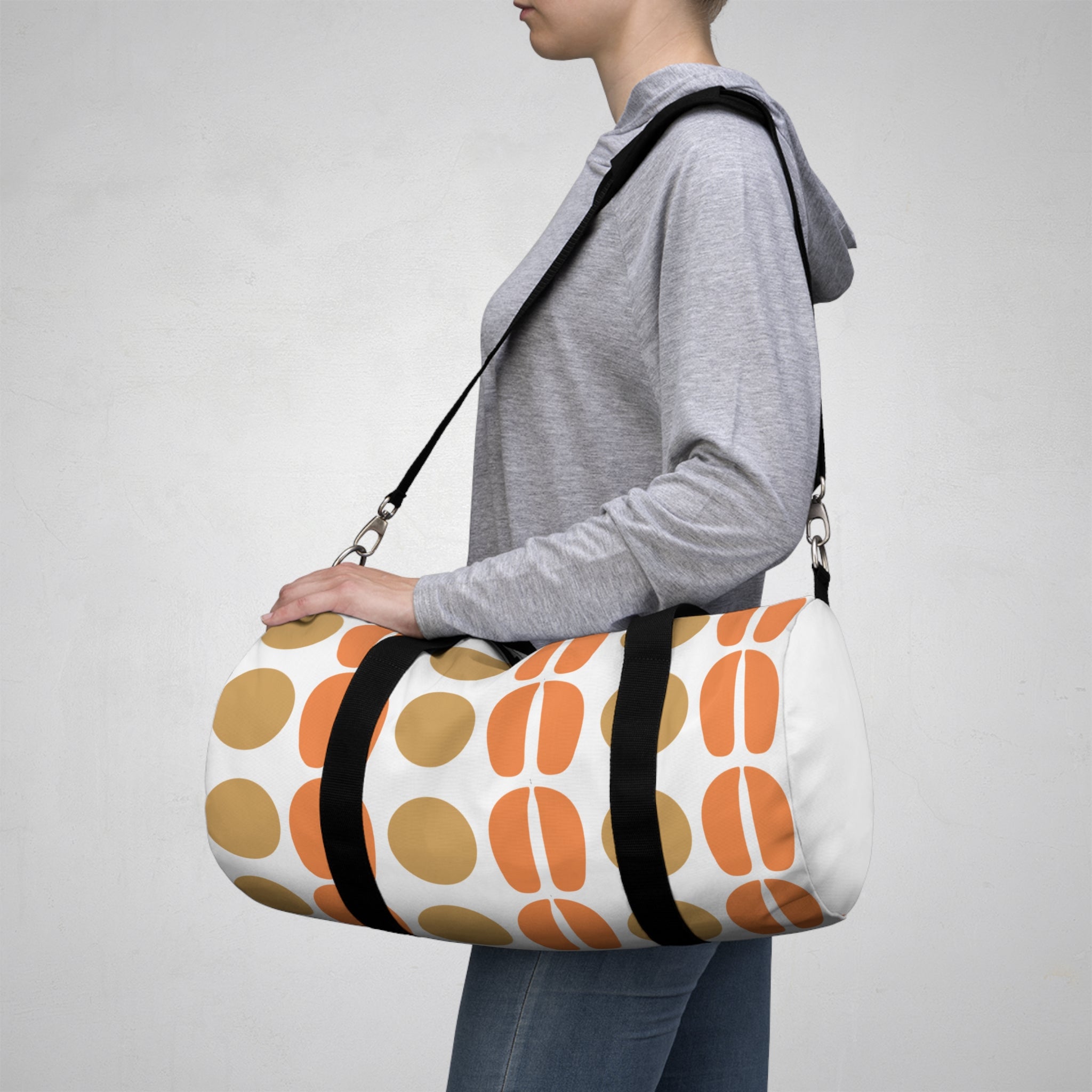 Person carrying a small white duffel bag with orange and brown patterns on a plain background