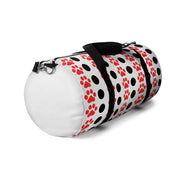 White duffel bag with red paw prints and black straps on a white background