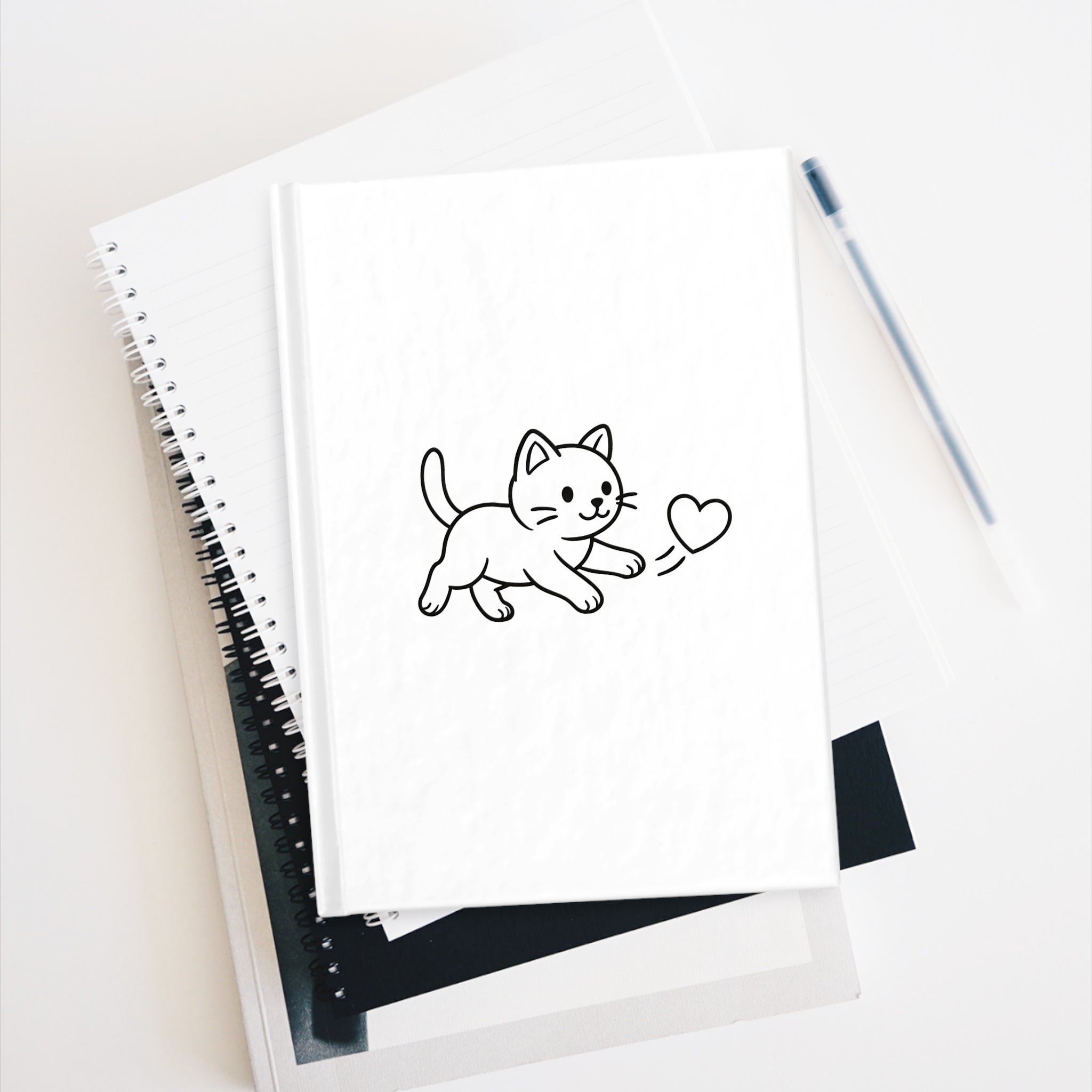 Notebook with a drawing of a cat holding a heart on a white surface.