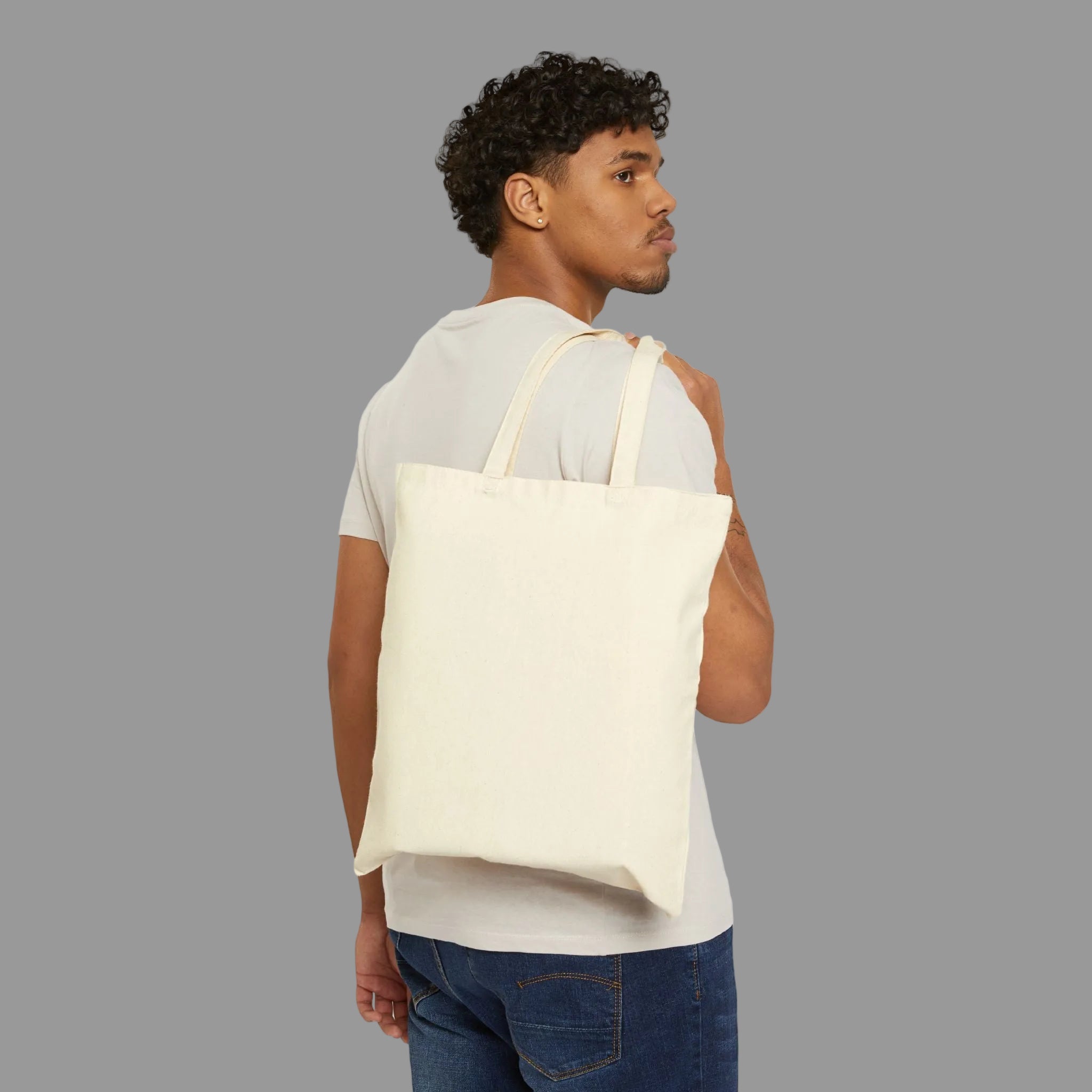 Man carrying a beige tote bag on a white background