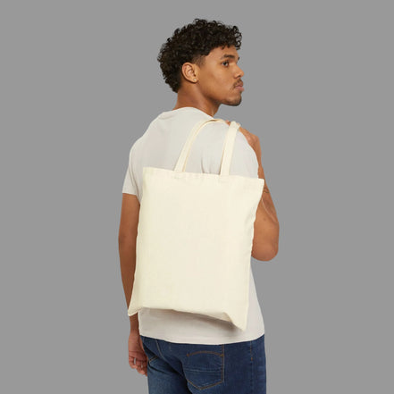 Man carrying a beige tote bag on a white background