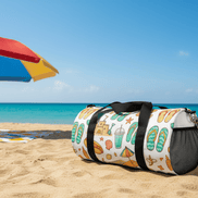 Beach themed duffel on sand with an umbrella at the beach