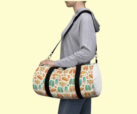 a woman has a summer theme duffel bag with hot dogs, flip flops, and sandcastles over her shoulder.
